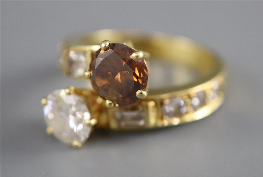 A modern yellow metal and two colour diamond two stone crossover ring,